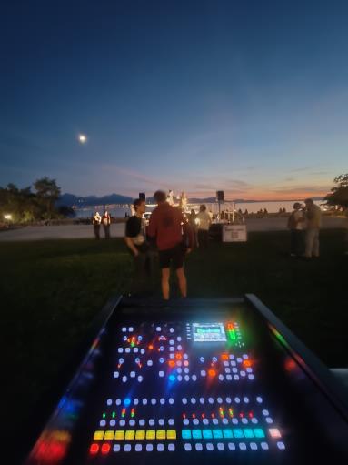 Console de mixage numérique illuminée, au crépuscule, lors d'un événement en plein air